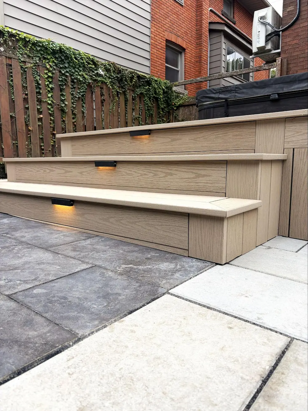 New deck steps with built-in step lights and a paver patio